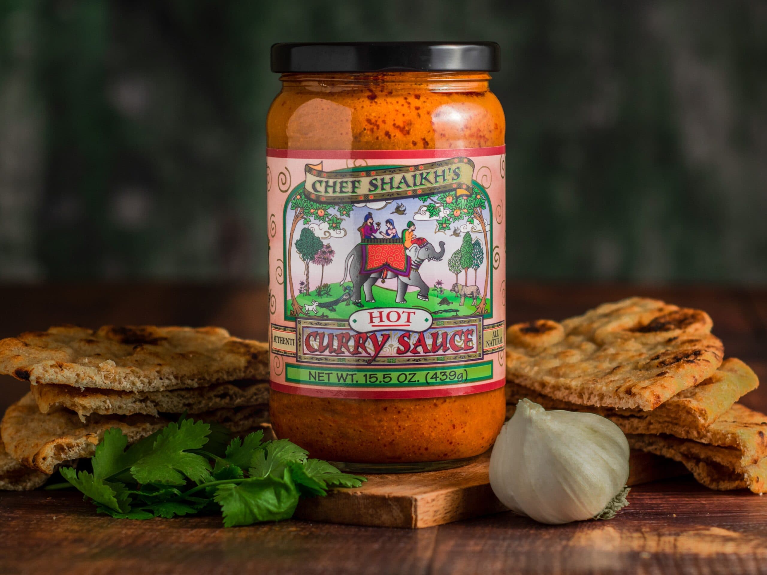 Jar of Chef Shaikh's Hot Curry Sauce with naan, garlic and cilantro