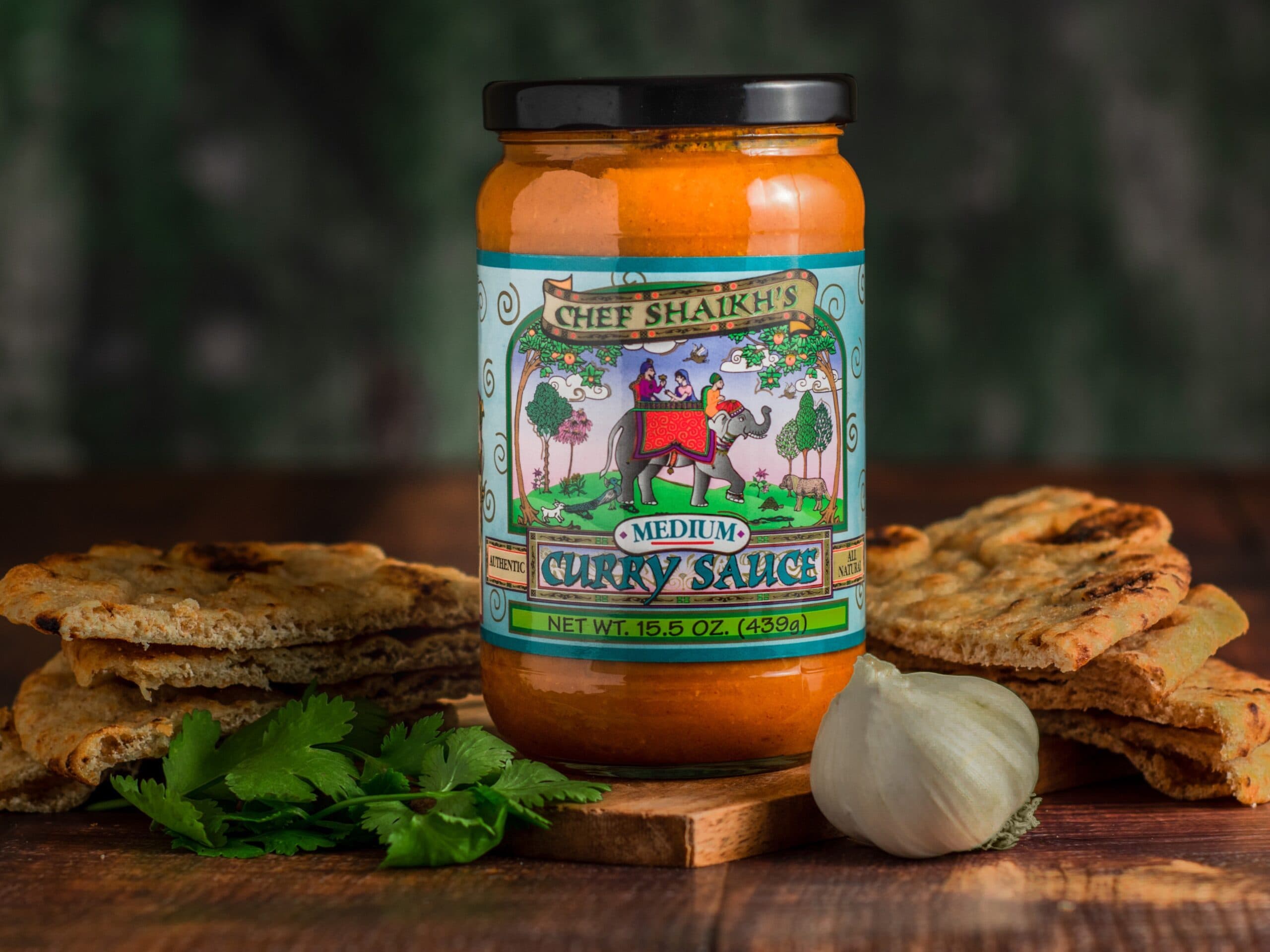 Jar of Chef Shaikh's Medium Curry Sauce with naan, garlic and cilantro