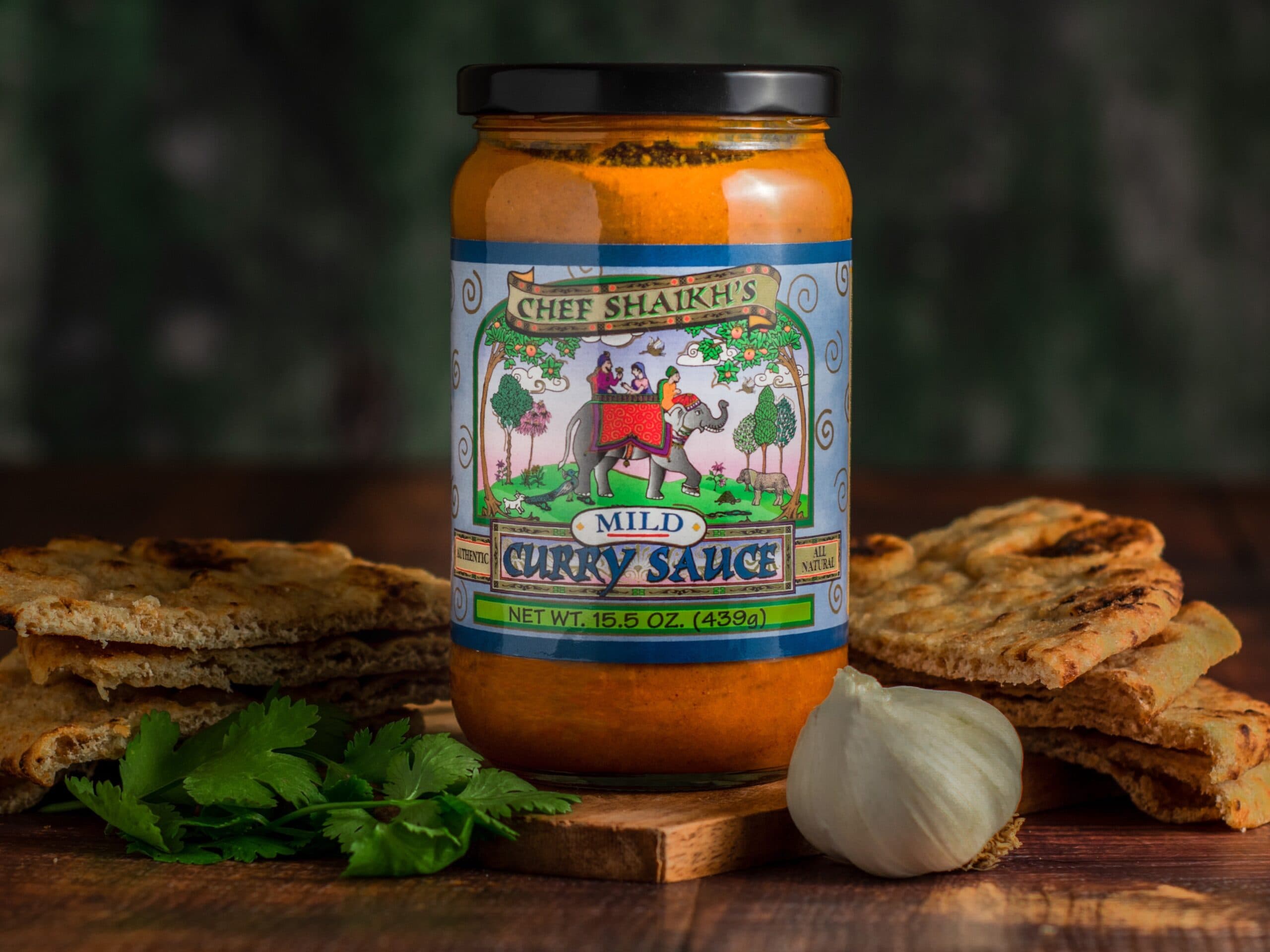 Jar of Chef Shaikh's Mild Curry Sauce with naan, garlic and cilantro